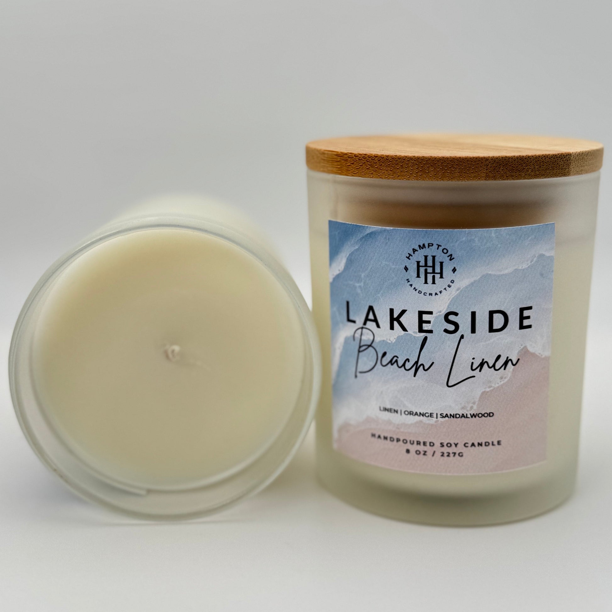 Candle with a wooden lid and 'Lakeside Beach Linen' label on a white background