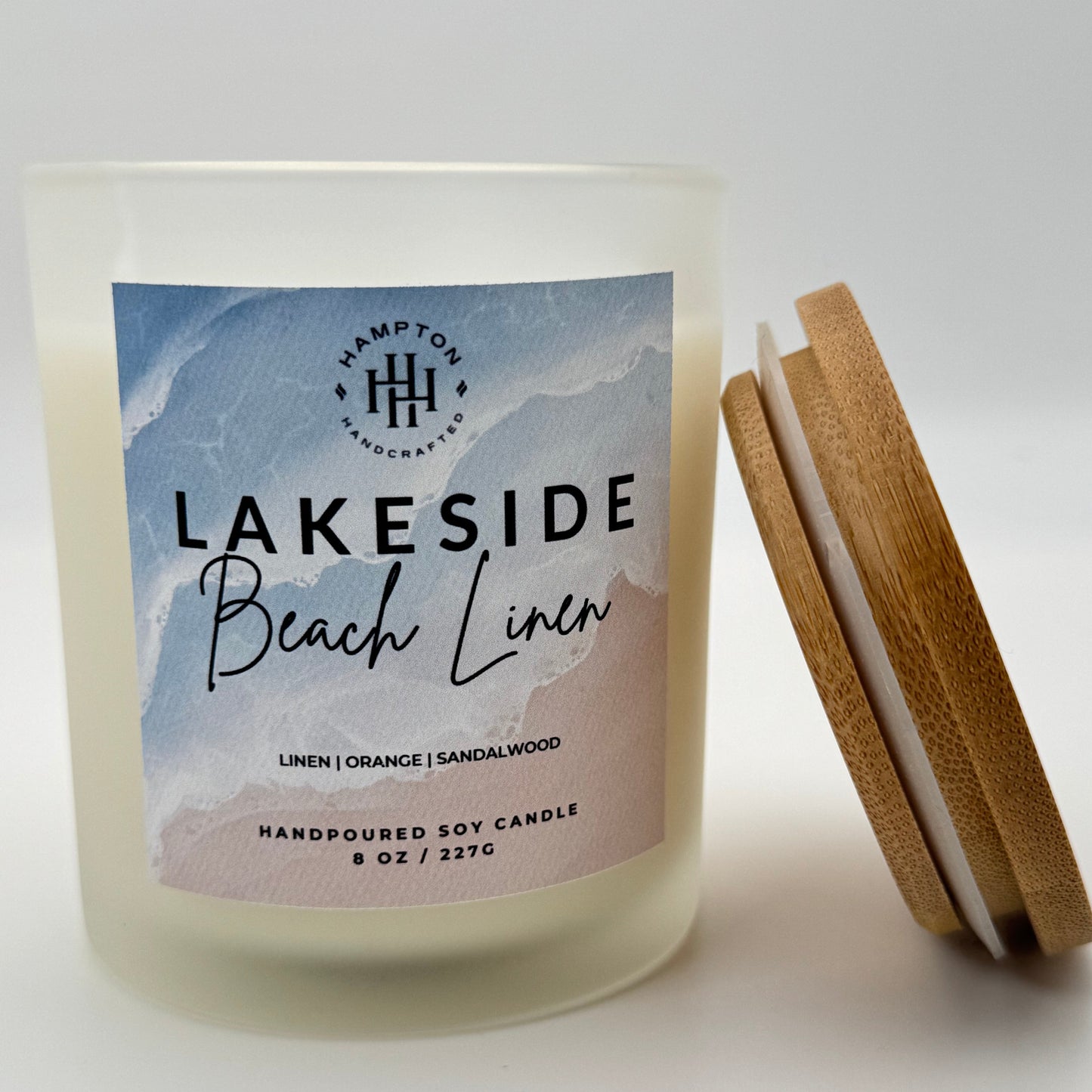 Candle labeled 'Lakeside Beach Linen' with wooden lid on a white background