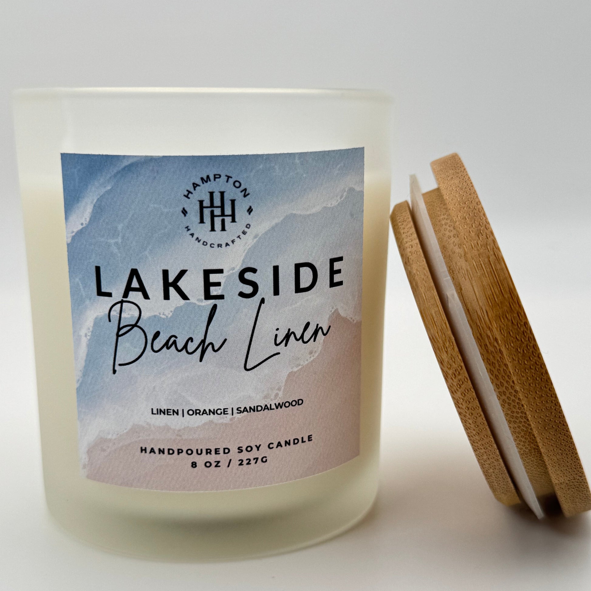 Candle labeled 'Lakeside Beach Linen' with wooden lid on a white background
