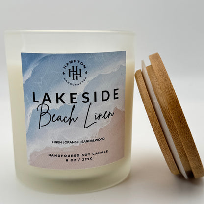 Candle labeled 'Lakeside Beach Linen' with wooden lid on a white background